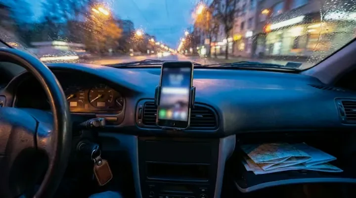 A phone in a dashboard mount inside a parked car at night